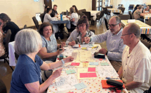 4 tables with 6 people at each, laughing while playing a game together