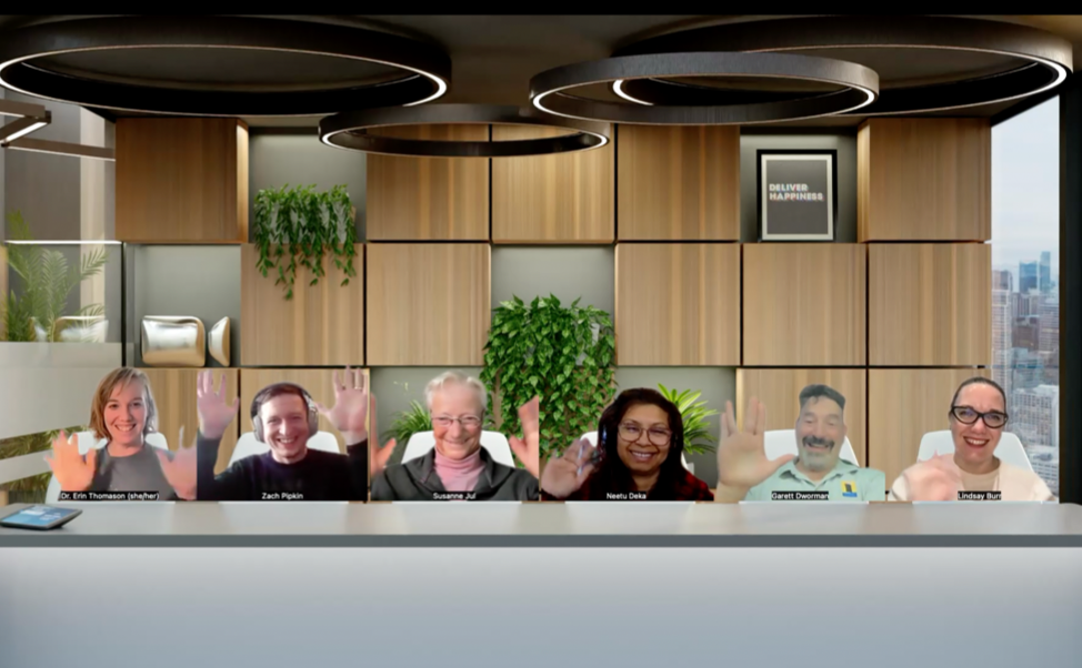 Zoom meeting capture of six people looking like they are seated side-by-side in a conference room, smiling and waving at the camera.
